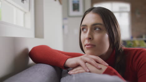 happy caucasian woman sitting on sofa in living room looking through window and smiling