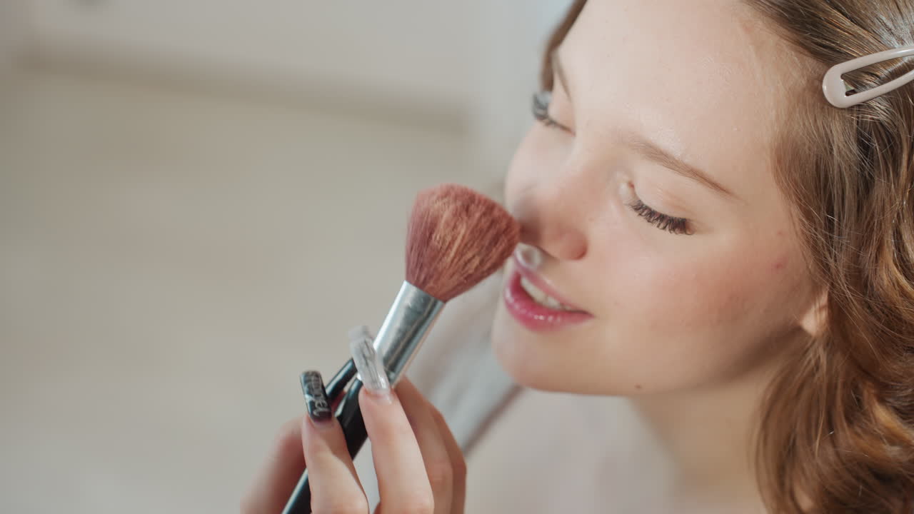 Gentle Cosmetic Preparation, Woman Softly Applying Makeup Outdoors, Serene Woman Enhancing Cheeks With Makeup Tools, Peaceful Woman Uses Makeup Brushes And Compact Before Heading Out For Day