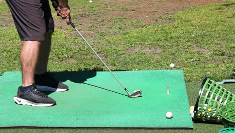 hombre practicando el swing de golf en la alfombra verde