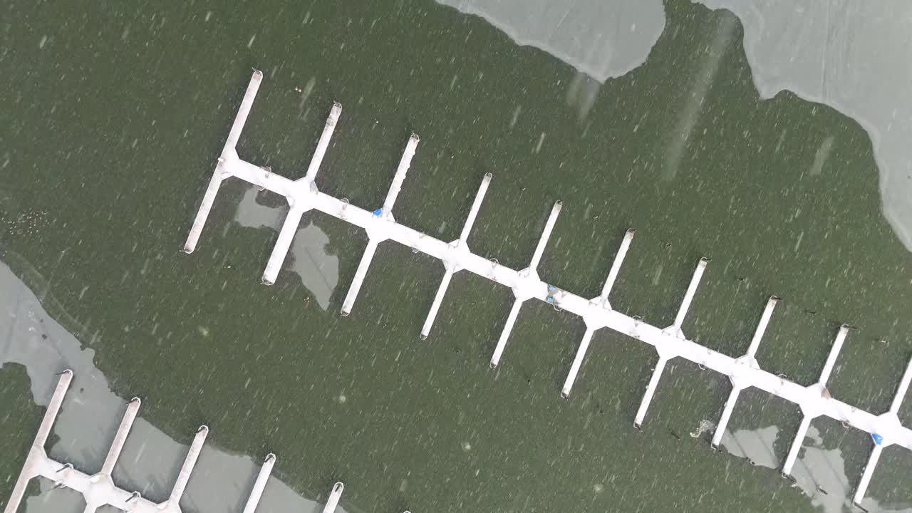 Aerial top down shot of a snow covered dock surrounded by ice.