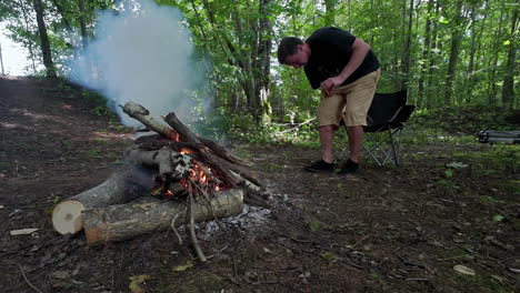 a man sits quietly in a camping chair close to the campfire