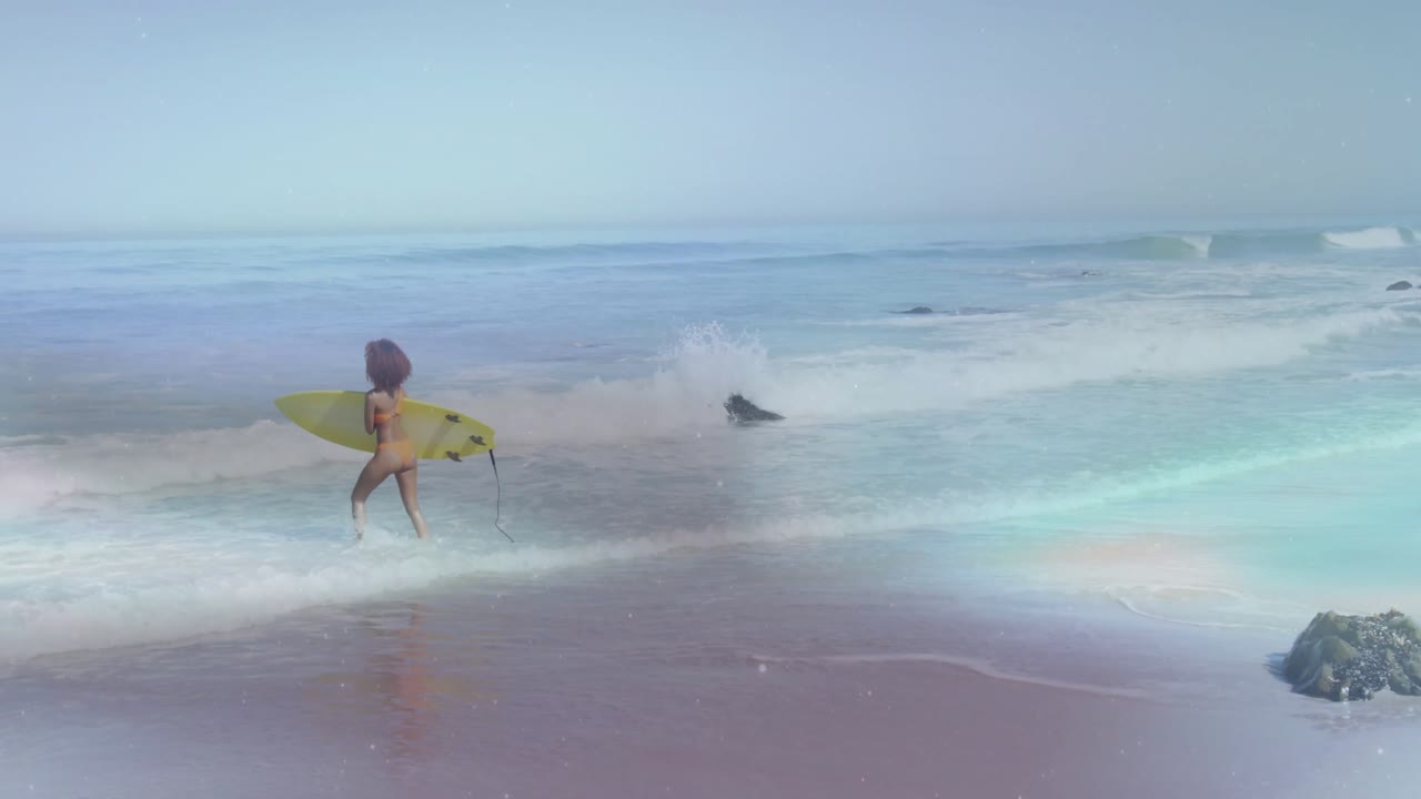 Surfista donna che entra tra le onde e trotterella, preparandosi a remare oltre le onde che si frangono con una tavola gialla.