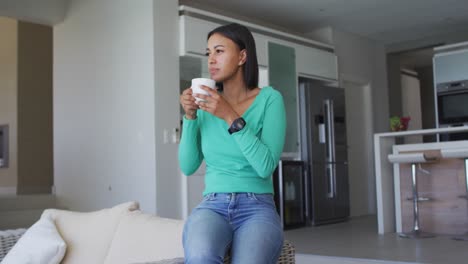 african american woman drinking coffee while sitting on the couch at home