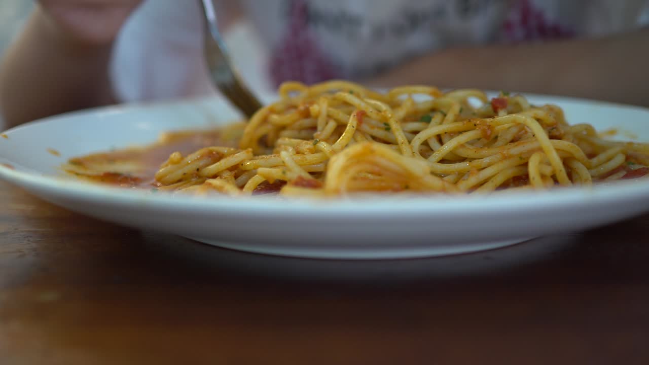una niña pequeña come espagueti de mariscos de tomate en un restaurante. el camión disparó de izquierda a derecha.