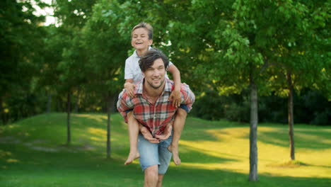 Boy-jumping-on-father-back-in-field