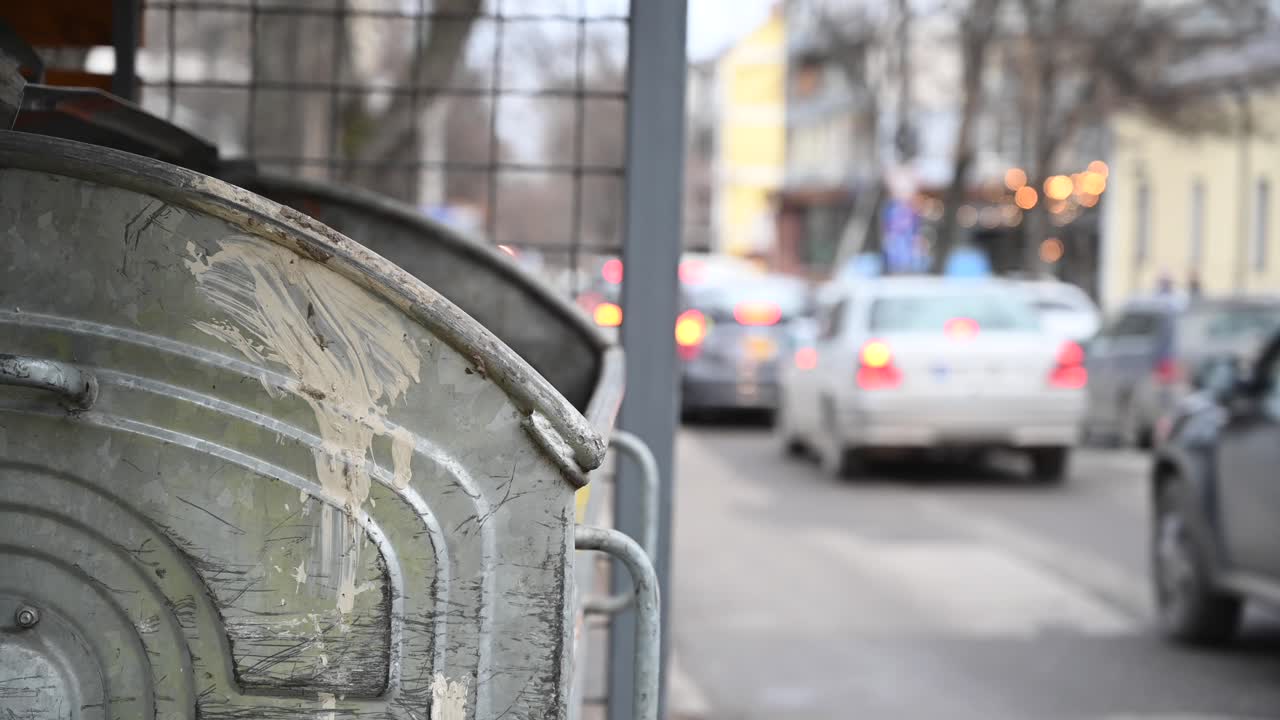 Trash bin on wheels with cars riding on background