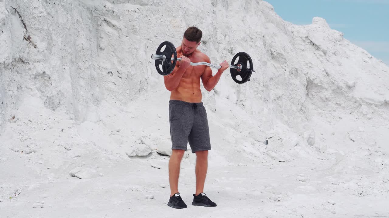 Exercise for biceps in nature. A man in shorts comes up and raises the bar