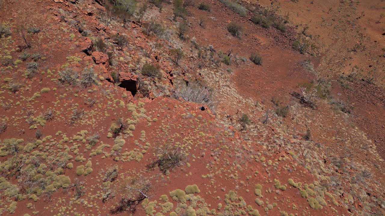 hombre sentado en el borde de la montaña rocosa contemplando el panorama en el desierto de australia occidental