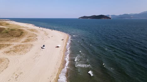 Slow-motion-aerial-clip-over-a-tropical-beach-with-golden-sand-in-the-area-of-Keramoti,-Kavala,-in-Northern-Greece-in-4k