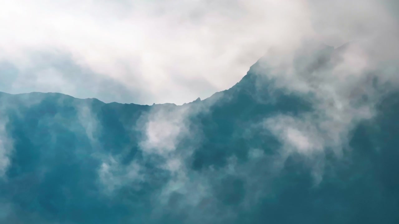 Aerial footage of clouds parting to reveal a dark blue-grey mountain silhouette, creating a misty, atmospheric reveal of the ridgeline.