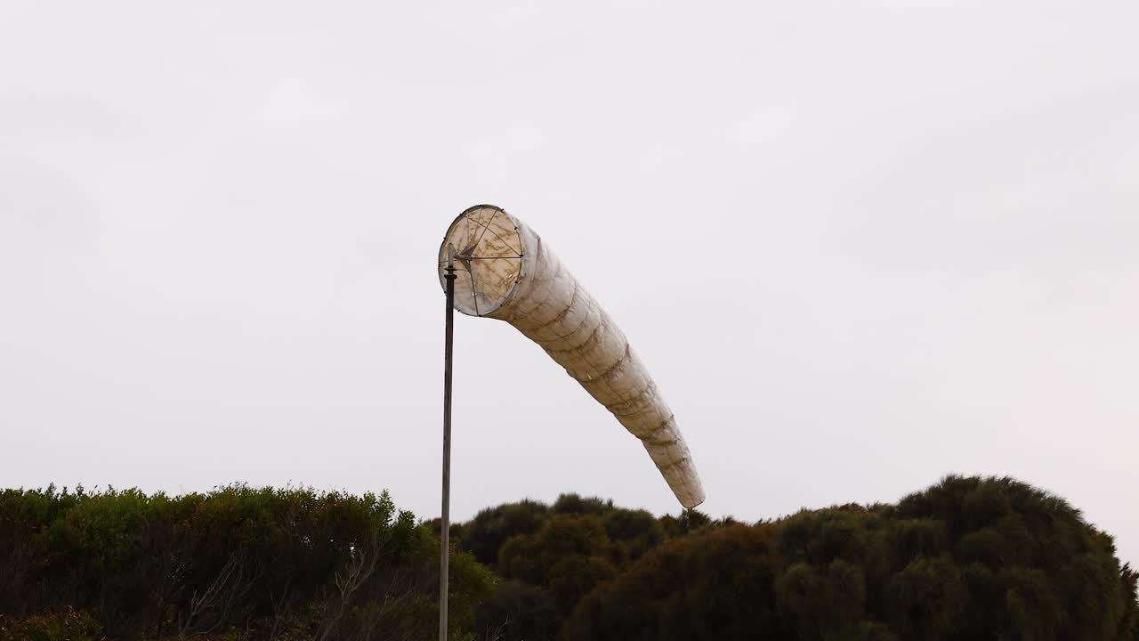 A windsock sways gently against a cloudy sky at Port Campbell, capturing the serene coastal atmosphere