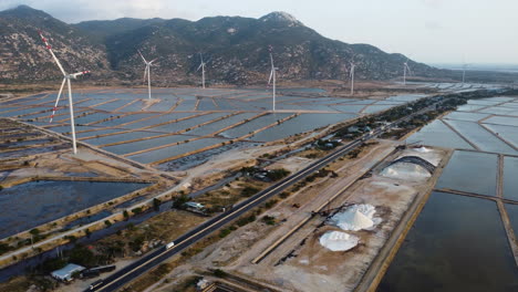 aerial panoramic view of wide salt fields and wind turbines, with a road crossing