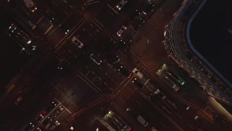 AERIAL:-Beautiful-Overhead-Shot-of-busy-intersection-at-night-with-Car-traffic-and-city-lights