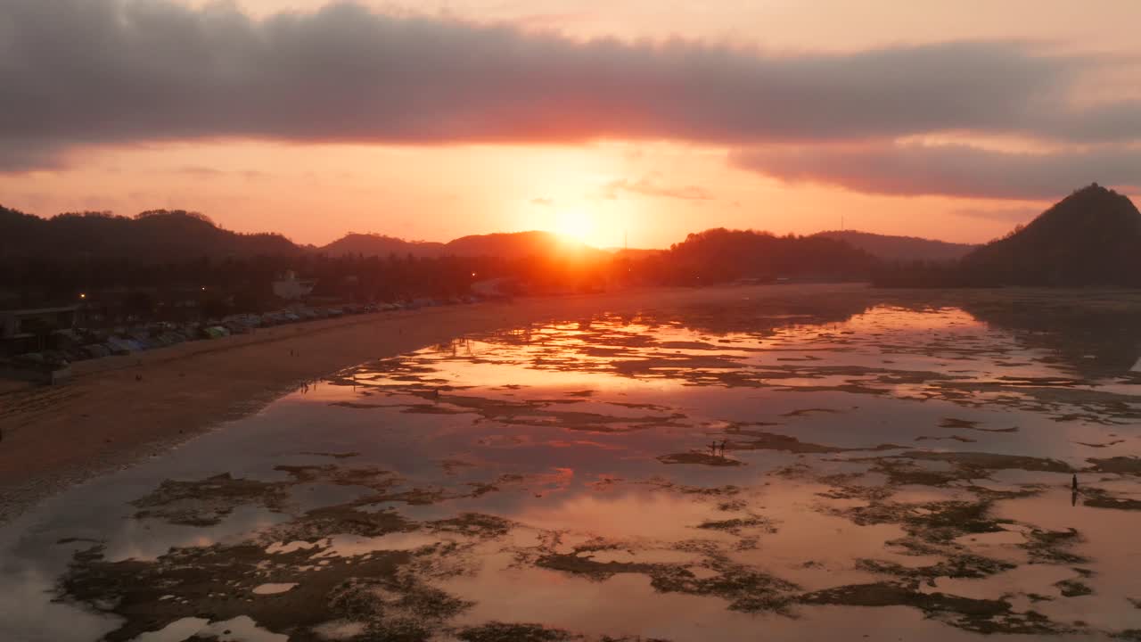 el arrecife seco de kuta lombok durante el amanecer, con gente local buscando comida y conchas marinas