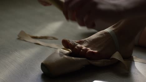 ballerina putting on pointe shoes