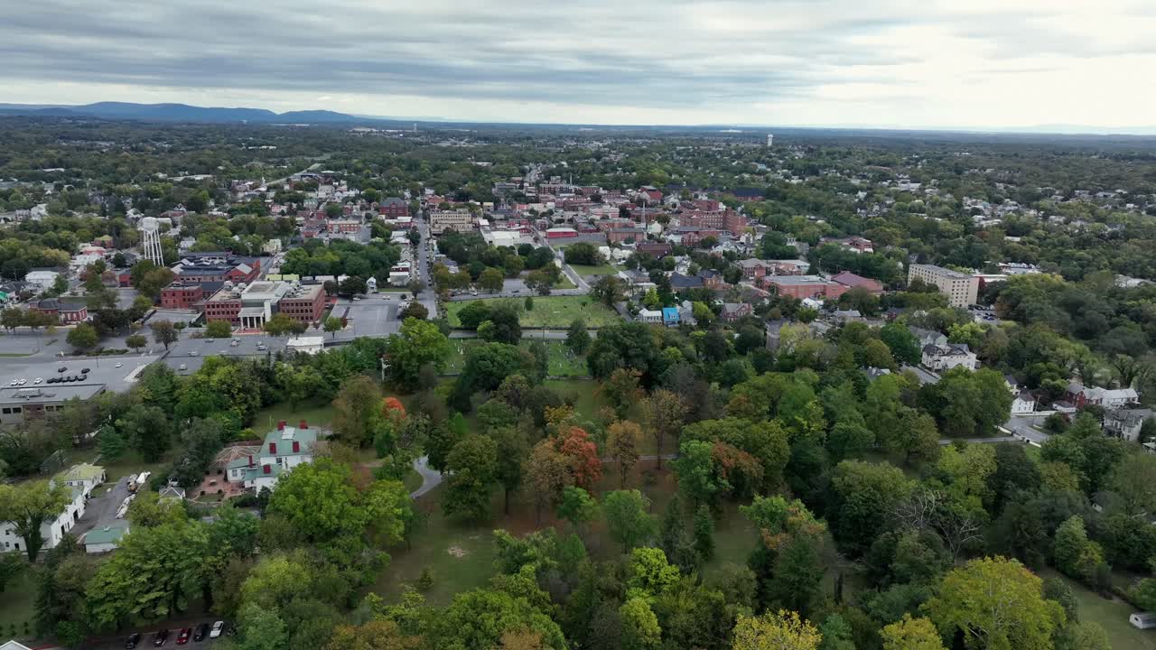 City Park of martinsburg with colored trees in autumn season. Downtown with historic buildings and water tower. West Virginia, USA. Aerial wide shot
