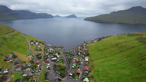 Aerial-descending-shot-reveals-Kvivik-village-in-front-of-Atlantic-Ocean-with-Koltur-Island-in-background