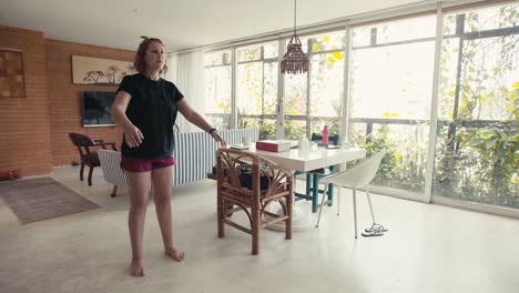 mujer joven haciendo sentadillas para perder peso en la luminosa sala de estar de su casa