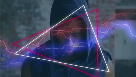 animation of colourful shapes over man wearing a hoodie in an abandoned building