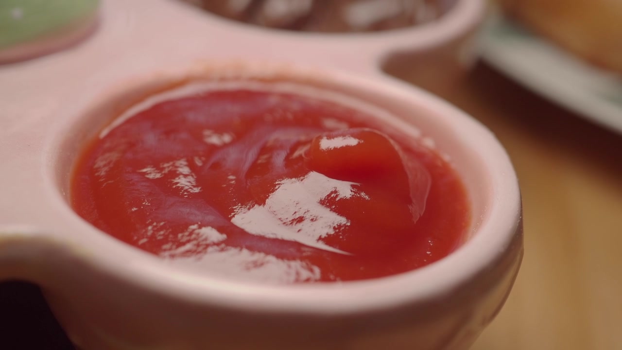 Primo piano di ketchup rosso in una piccola ciotola rosa