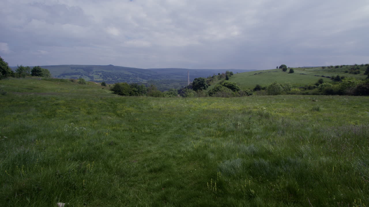 Vast Green Fields and Rolling Hills Under a Cloudy Sky