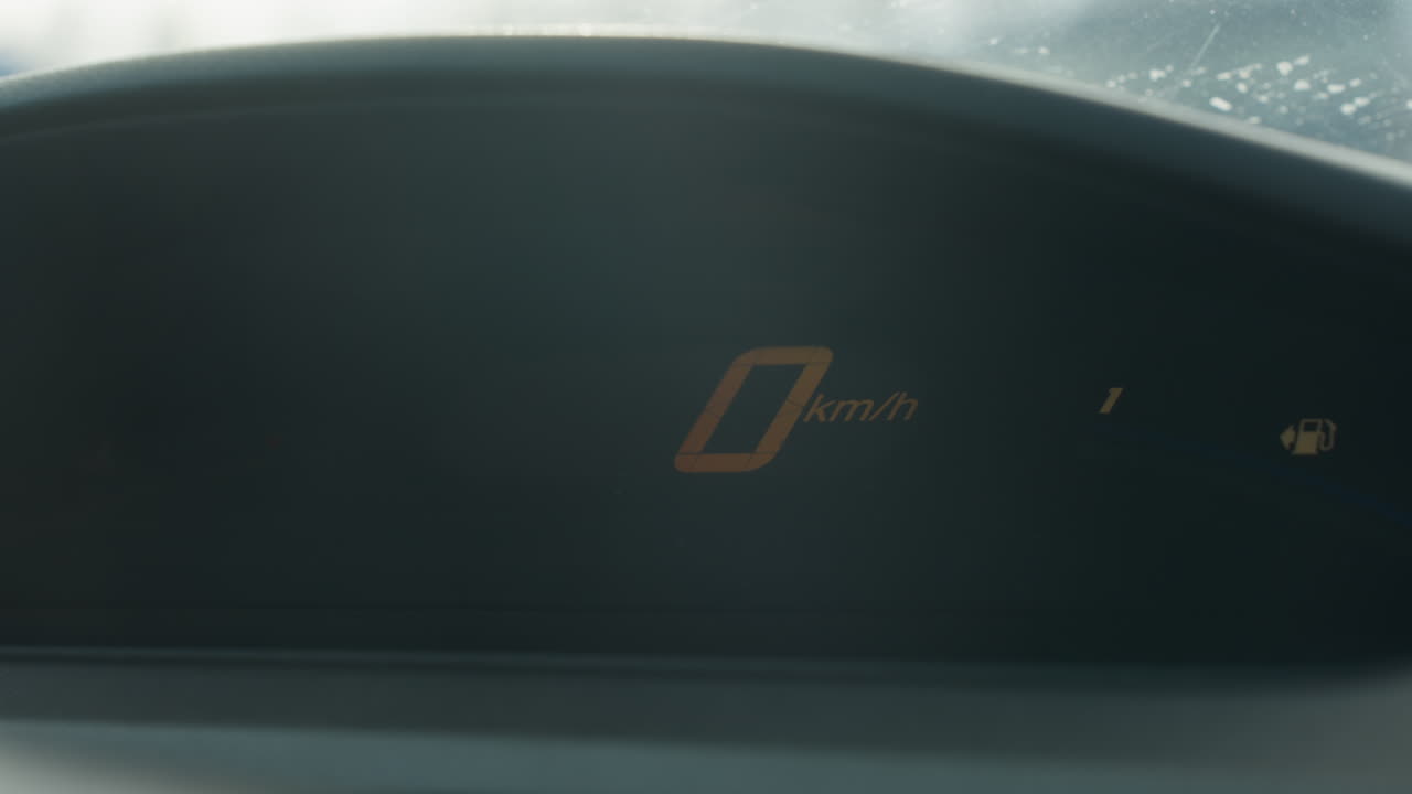Close up digital speedometer displays blinking triple digit readout then resets to zero kmh gauge flicker ambient dashboard glare frozen panel background blur dynamic interior shot focus