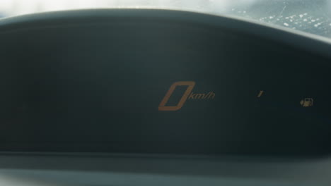 close up digital speedometer displays blinking triple digit readout then resets to zero kmh gauge flicker ambient dashboard glare frozen panel background blur dynamic interior shot focus