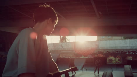 Young-man-having-break-after-training-at-skatepark.-Man-looking-at-camera.