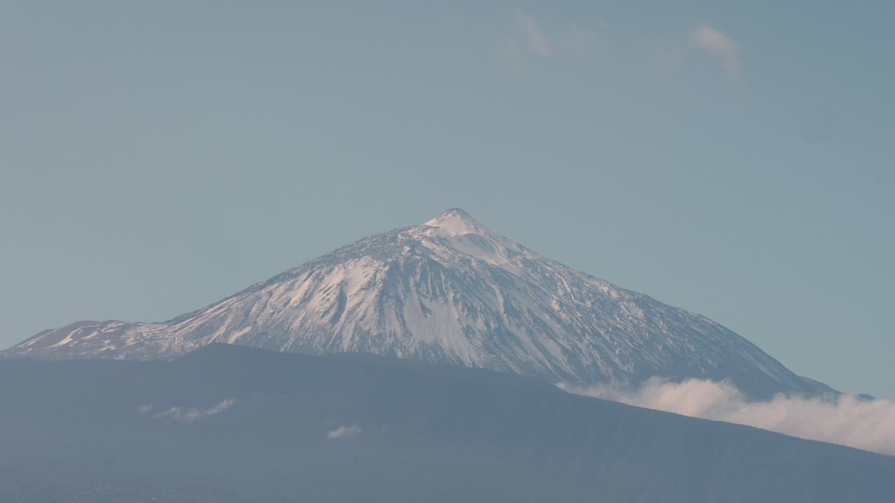 Daytime timelapse view of Mount Teide volcano from Mirador del Pris in Tenerife, Canary Islands. Snow-capped peak under clear blue sky