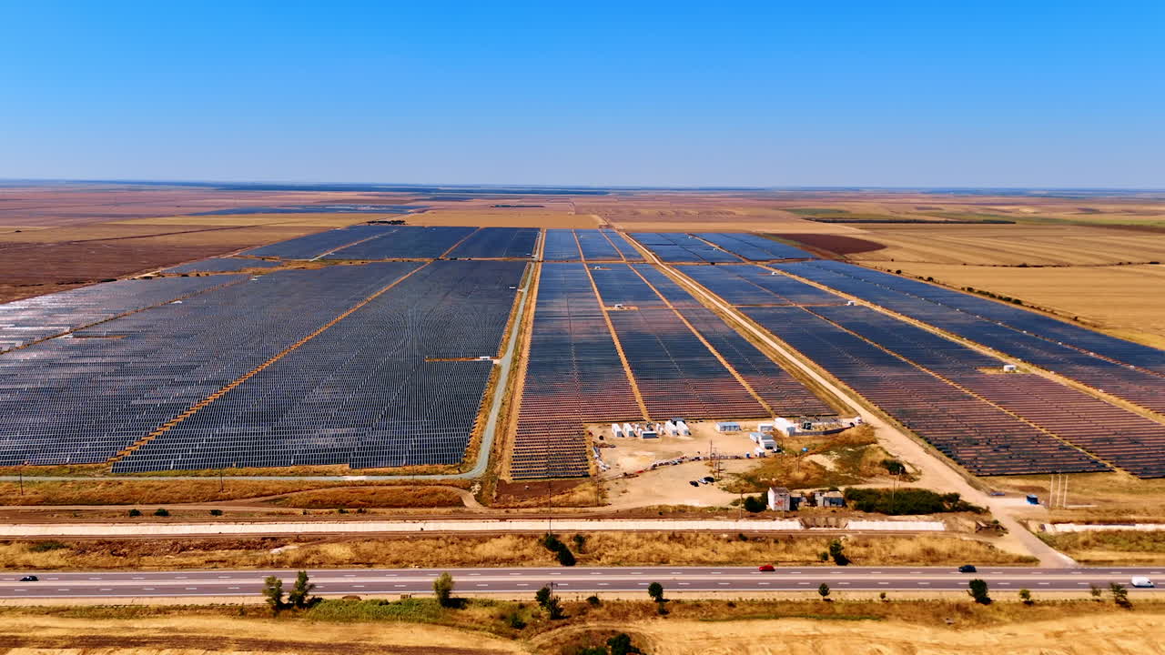 Vast solar panel farm in sunny landscape. A large solar panel farm stretches across the landscape under a clear blue sky, showcasing renewable energy efforts