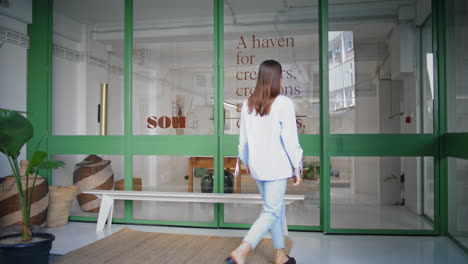 woman entering store gallery on weekend. young visitor walking city building