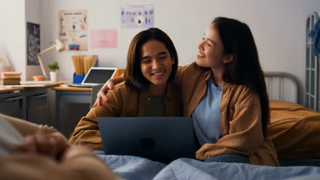 Happy Young Couple Using Laptop in Dorm Room
