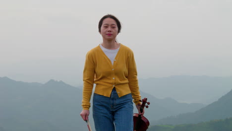 woman-smiles-moving-toward-the-camera-as-she-leaves-the-mountain-top-stage-after-playing-her-violin