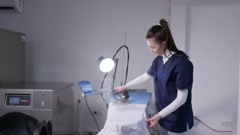 female cleaner ironing clothes at laundry shop