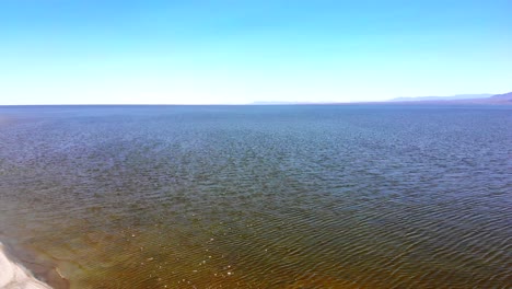 salton sea long 4k aerial drone pull back from salty still waters over dead beach and brackish pond in desert in southern california