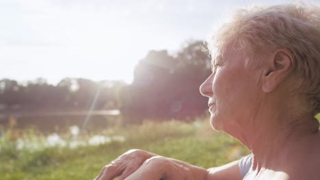 Senior-woman-sitting-in-the-sun-in-the-park-and-looking-around