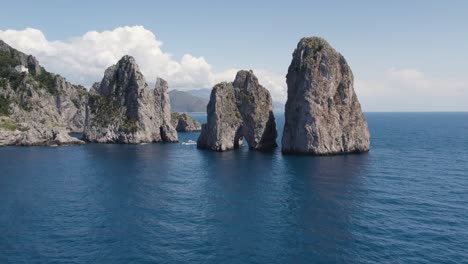 Aerial-view-of-iconic-Faraglioni-sea-stacks-on-Capri-coastline,-Italy