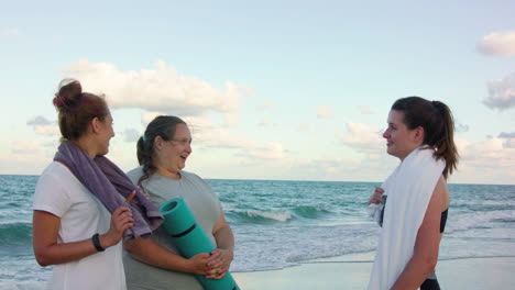 Three-girls-in-sportive-clothes-talking-on-the-beach.