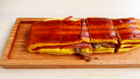 delicioso sándwich portugués en tabla de madera cortado en pedazos para comer, de cerca
