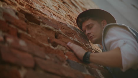 man leaning against a brick wall