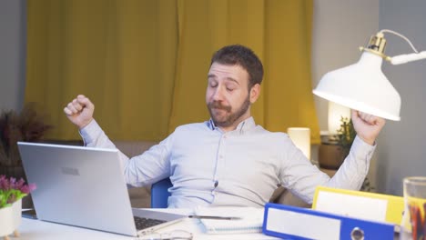 Home-office-worker-man-yawns-and-relaxes-at-the-camera.