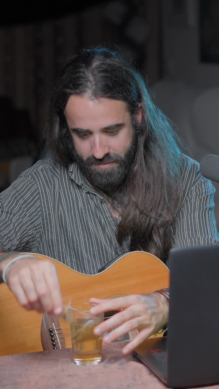 Man Prepares Tea While Holding an Acoustic Guitar