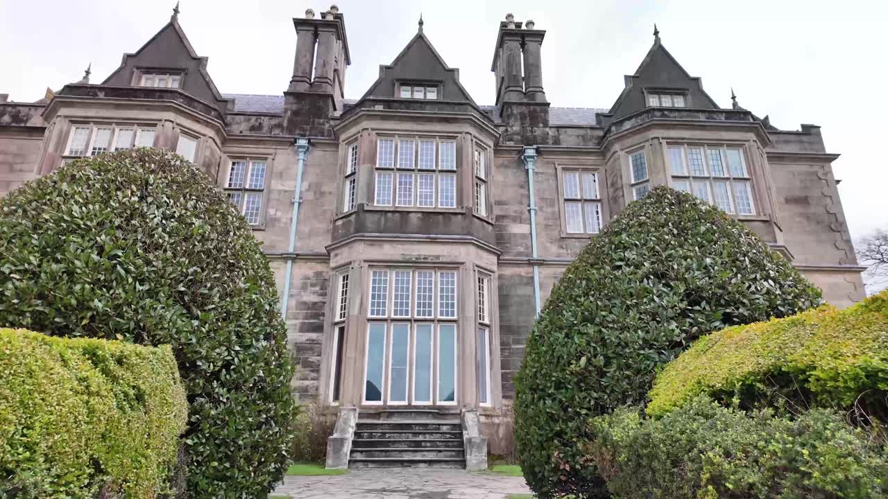 Killarney's landmark Muckross house entrance with stairs and trimmed bushes. National park Ireland