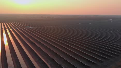 aerial drone view of large solar panels at a solar farm at bright sunset in early winter. solar cell power plants