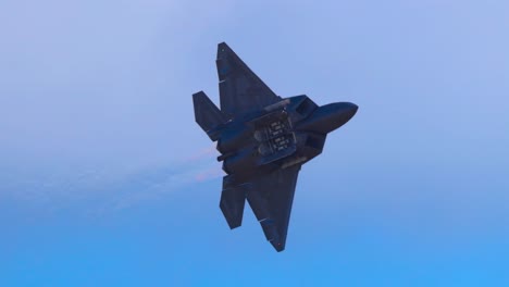 f-22 raptor executes dynamic aerial maneuvers against a clear blue sky, showcasing agility and power in a 10-second sequence