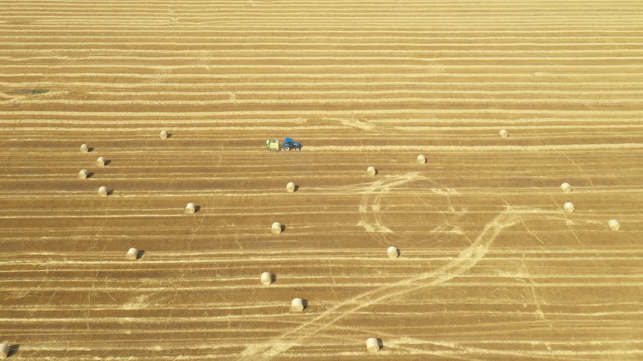 Aerial view of tractor tow trailed bale machine to collect straw from harvested field