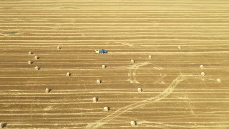 aerial view of tractor tow trailed bale machine to collect straw from harvested field