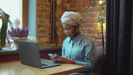 black businesswoman using phone while working in cafe