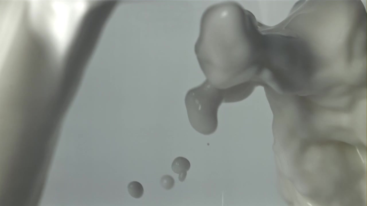 Em câmera lenta: Close-up de líquido branco derramando e espirrando
