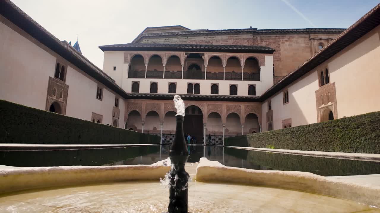 Static close-up shot of the fountain with a view of the south façade of the Patio de los Arrayanes in the monumental complex of the Alhambra in Granada, Spain